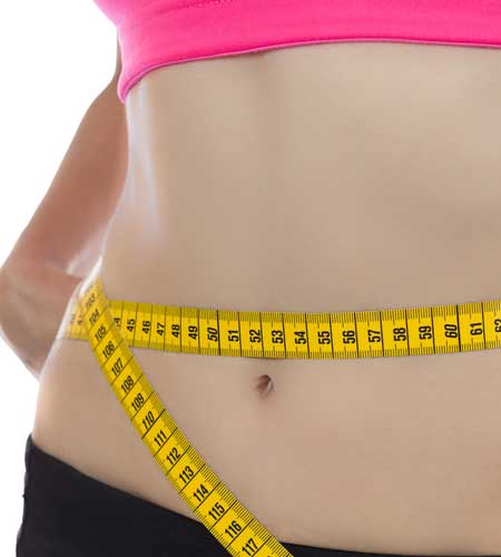 Fit woman measuring waist with yellow tape measure, as a small part of a complte body composition analysis, like that provided by Private Health Dallas.